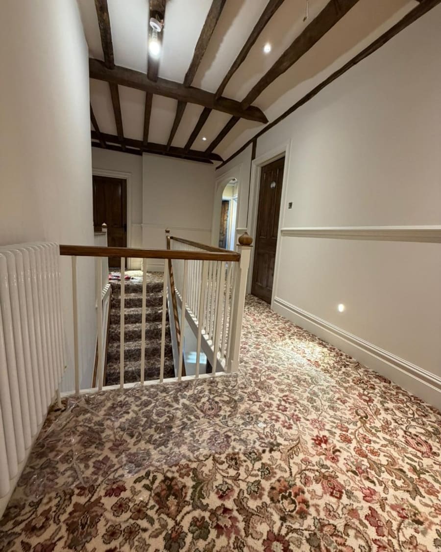 After — refreshed landing with white spindles and exposed ceiling beams