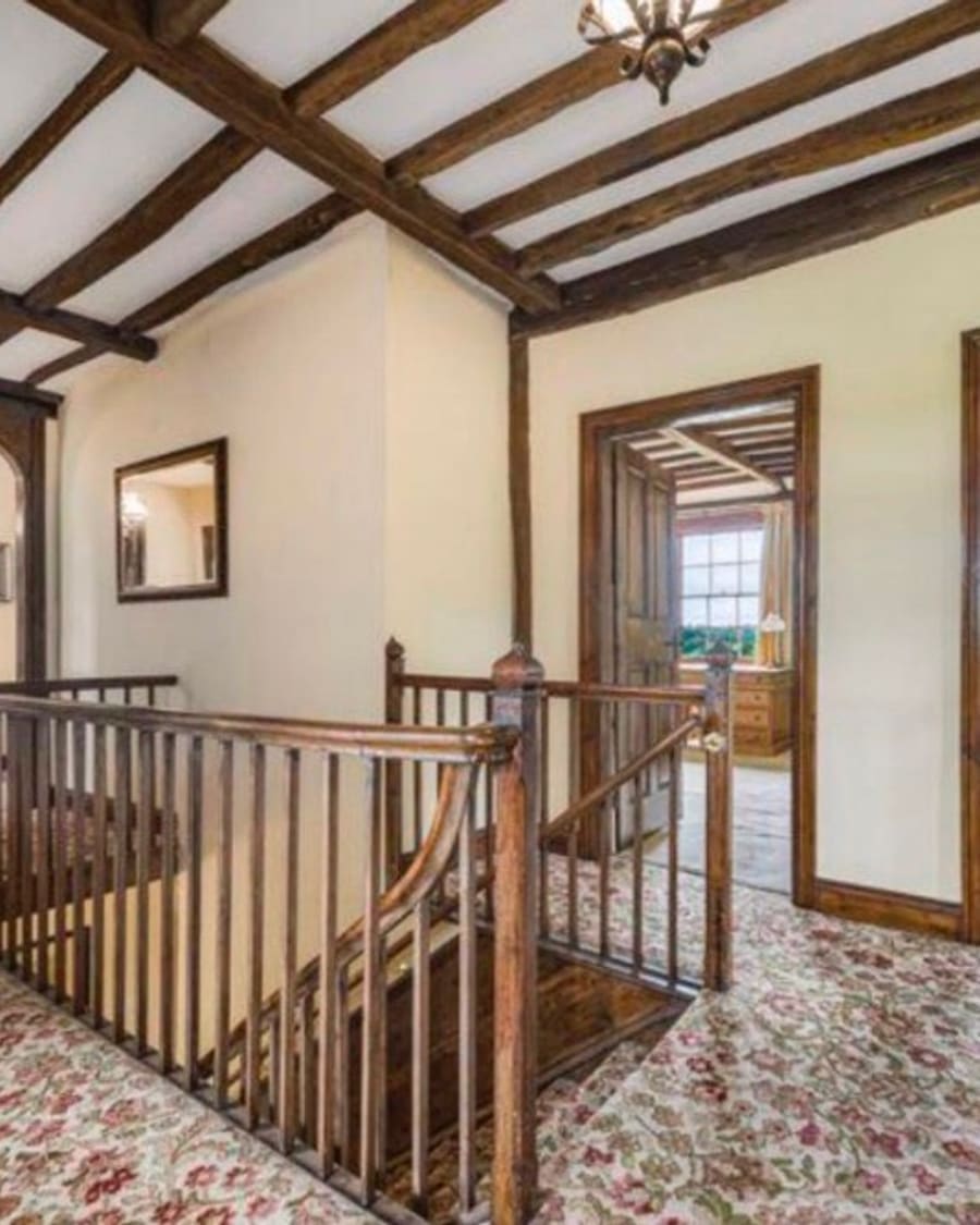 Before — landing with dark wood staircase, beams and dated carpet