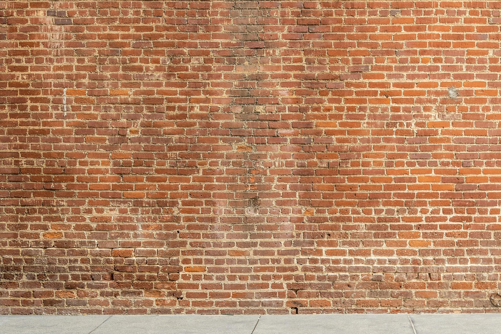 Detailed image of a textured red brick wall with a concrete base, ideal for architectural and design backgrounds.